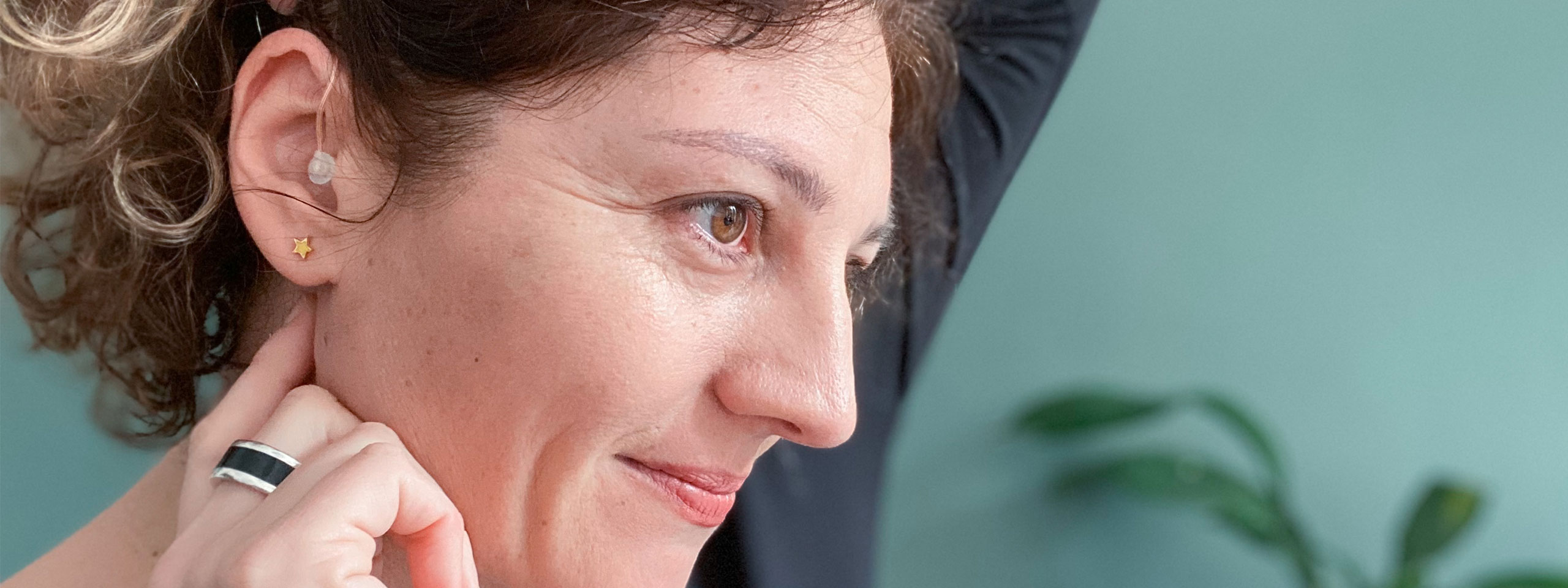 Frau zeigt ihr Hörgerät